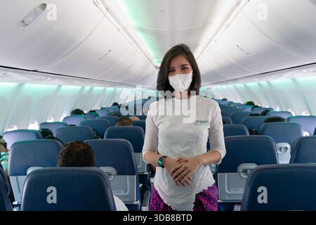Sepang, Malesia - 19 maggio 2023: Un assistente di volo Batik Air che indossa una maschera facciale si trova nella corsia a bordo di un aeromobile Boeing 737-8 MAX. Foto Stock