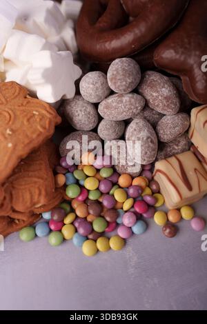 un delizioso assortimento di cioccolatini colorati ricoperti di caramelle, biscotti speziati, cioccolatini smerigliati e soffici marshmallow che creano un'atmosfera festosa Foto Stock