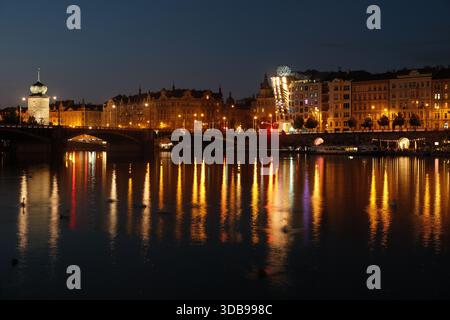 Bellissimo paesaggio urbano di Praga di notte, con luci colorate che si specchiano sulla tranquilla superficie del fiume Moldava. Foto Stock
