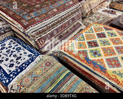 Assortimento di vivaci tappeti e tappeti dell'Asia centrale a motivi geometrici Foto Stock