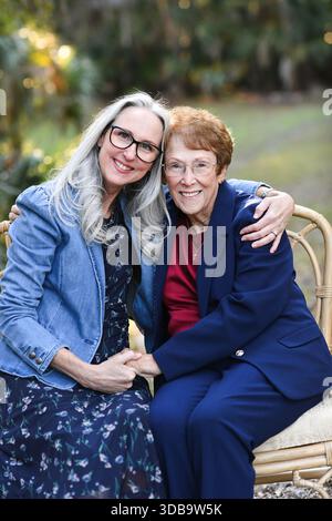 Sorridendo donne anziane sedute a stretto contatto su una panchina all'aperto Foto Stock