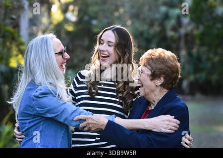 Tre generazioni di donne che ridono e abbracciano all'aperto. Foto Stock