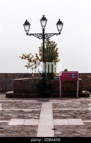Un primo piano verticale centrato di un bellissimo lampione triplo in vecchio stile su una piazza in pietra e piastrellata nell'Alhambra, Ciudad Real. Foto Stock