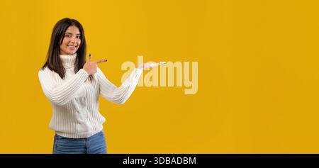 Gesti femminili sorridenti su sfondo giallo brillante in un comodo pullover Foto Stock