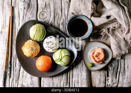 Sushi Temari. Polpette di sushi alla moda con salmone, avocado, cetriolo e omelette giapponesi su piatto di ceramica marrone. Salsa di soia, zenzero sottaceto, bacchette, li Foto Stock