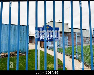 Manchester, Regno Unito - 15 novembre 2025: Ingresso pedonale in una scuola elementare di Manchester incorniciata da un cancello blu e recinzione metallica. Foto Stock