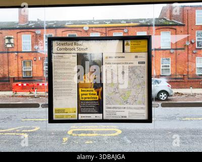 Manchester, Regno Unito - 15 novembre 2025: Esposizione dei trasporti pubblici in una strada di Manchester con orari e pannelli cartografici. Foto Stock