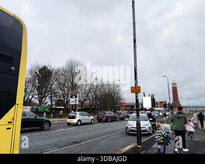 Manchester, Regno Unito - 15 novembre 2025: Affollata Manchester Street con autobus, automobili, pedoni e una torre lontana. Foto Stock