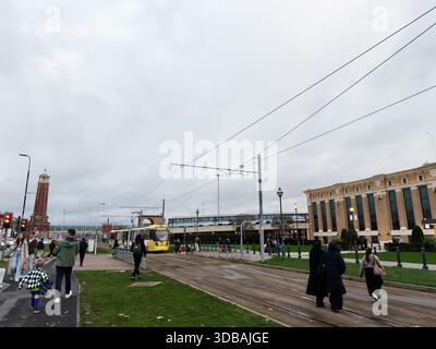 Manchester, Regno Unito - 15 novembre 2025: Scena all'aperto a Manchester con pedoni e un tram giallo vicino a binari ed edifici. Foto Stock