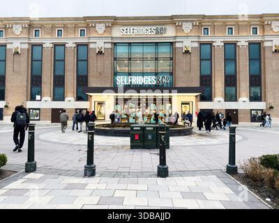 Manchester, Regno Unito - 15 novembre 2025: Gli amanti dello shopping vicino all'ingresso di Selfridges in una vivace Manchester plaza; il fronte urbano e la facciata in vetro. Foto Stock