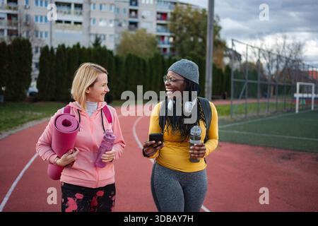 Diverse donne e amiche che camminano insieme sulla pista da corsa Foto Stock