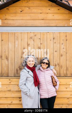 Le amiche donne anziane sorridono e abbracciano, si godono la loro compagnia all'aperto Foto Stock