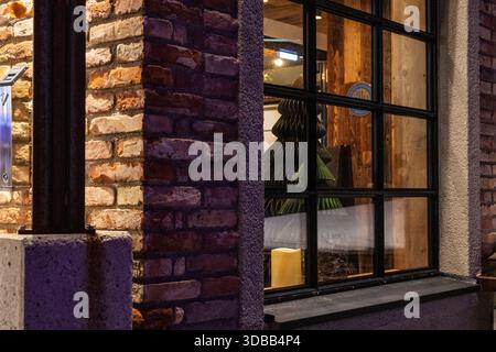 Una vista incantevole attraverso una finestra che mostra un'esibizione natalizia. Un albero di Natale stilizzato si erge illuminato su uno sfondo rustico in legno Foto Stock