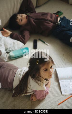 Fratelli e sorelle informali che trascorrono momenti tranquilli sul pavimento del soggiorno Foto Stock
