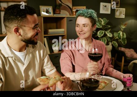 Giovane donna e giovane uomo che si godono la cena e bevono vino rosso insieme Foto Stock