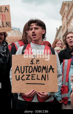 Il giovane manifestante ha un segno critico sulla mancanza di autonomia universitaria durante una manifestazione studentesca filo-palestinese nei pressi dell'Università di Varsavia. Foto Stock