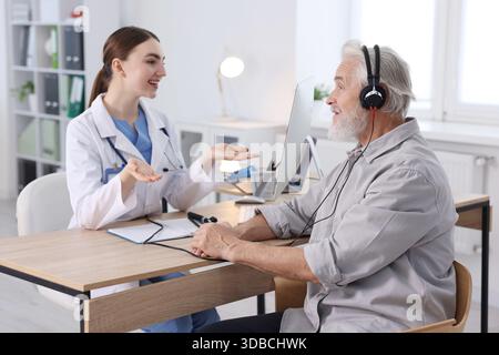 Paziente con cuffie audiometriche sottoposto a test uditivo in clinica Foto Stock