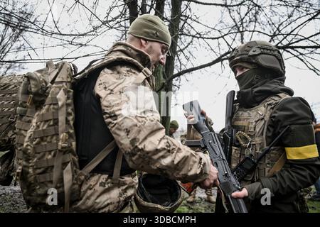 Un istruttore consegna un'arma a una recluta durante la "giornata zero" di addestramento di base sulle armi combinate presso la 65a brigata meccanizzata separata in un campo di addestramento improvvisato, Ucraina, il 12 dicembre 2025 (foto di Dmytro Smolienko/Ukrinform) Foto Stock