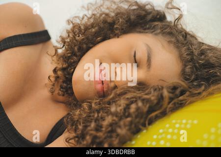 Giovane donna con capelli ricci che dorme pacificamente Foto Stock
