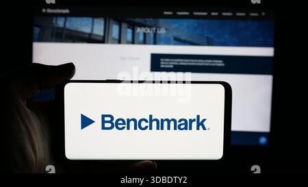 In questa immagine, una persona ha in mano un cellulare con il logo della società statunitense benchmark Electronics Inc. Sullo schermo davanti alla pagina Web. (Foto di Timon Schneider / SOPA Images/Sipa USA) *** esclusivamente per notizie editoriali *** Foto Stock