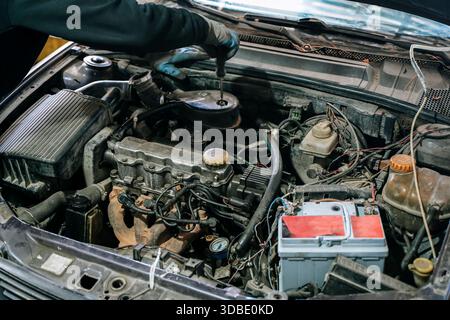 Restauro del motore per auto d'epoca. Riparazione e manutenzione del vecchio veicolo usato. Una vista dettagliata del motore di un'auto d'epoca sotto il cofano, che mostra le parti meccaniche di un classico veicolo usato in fase di restauro. Concentrarsi sulla manutenzione automobilistica, sulla riparazione dei motori e sul processo di rilancio delle vecchie automobili di seconda mano in un'officina Foto Stock