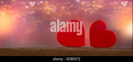 Primo piano di due forme di cuore con bokeh del cuore sfocato sullo sfondo Foto Stock