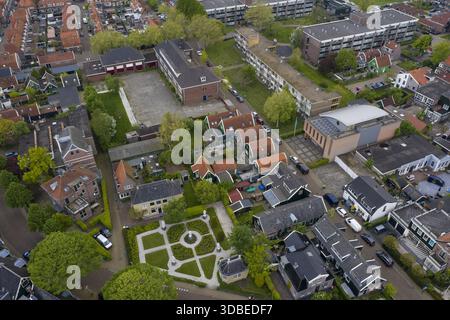 Vista aerea delle tradizionali case olandesi con tetti di tegole rosse e un giardino progettato meticolosamente, annidato tra edifici moderni, Zaandijk, Zaandam, ne Foto Stock