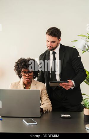 Due professionisti aziendali si sono impegnati in una discussione produttiva utilizzando un notebook per analizzare dati e strategie sul lavoro, mostrando il lavoro di squadra e. Foto Stock