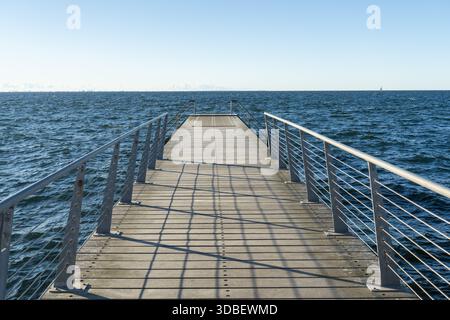 La vista di un molo di legno si estende nel mare blu scintillante sotto un cielo limpido, gettando lunghe ombre, Vastra Hamnen, Malmo, Svezia. Foto Stock