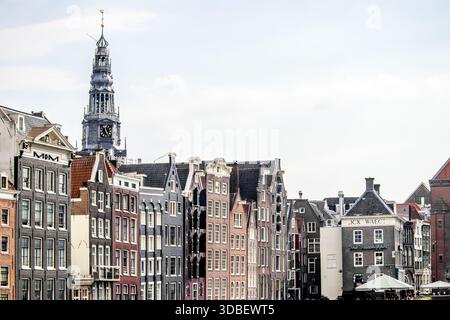 Vista delle case colorate e strette sul canale con i frontali a gradini fiancheggiano il lungomare sotto un cielo luminoso, una storica torre della chiesa che sorge sullo sfondo, AM Foto Stock