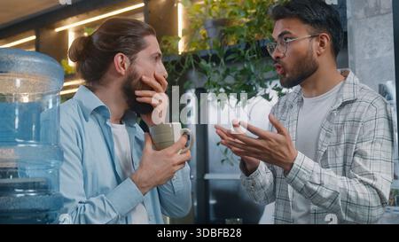 Due uomini di diversità colleghi di lavoro occasionali che parlano pausa pausa pausa in ufficio caffè uomo arabo che parla notizie Caucasico maschio shock eccitato stupito Foto Stock