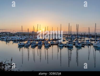 Tramonto sul porto di Troon con numerose barche a vela, acque calme e riflessi dorati sul porto. Foto Stock