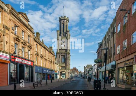 Vista diurna di Ayr High Street con una storica torre dell'orologio, negozi e pedoni. Foto Stock