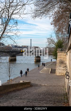 Persone che camminano e fanno jogging lungo la Senna con sullo sfondo la Torre Eiffel in una giornata di sole d'autunno Foto Stock