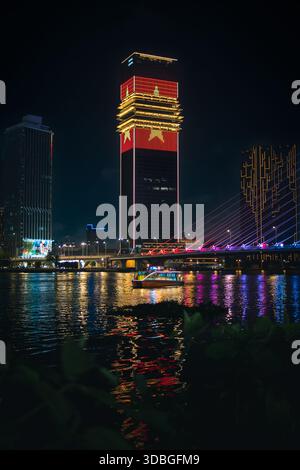 Lo skyline notturno della città di ho chi Minh con il ponte Ba Son illuminato sul fiume Saigon e il grattacielo che mostra la bandiera vietnamita. Tour in barca sull'acqua. Foto Stock