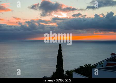Tramonto su Madeira vicino a Funchal con cipressi e tetti di tegole rosse Foto Stock