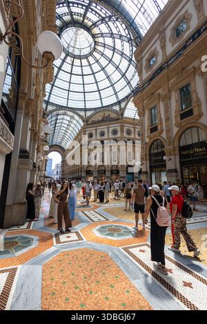 MILANO, ITALIA, 06.19.2025: Gli amanti dello shopping e i visitatori camminano sotto le facciate ornate all'interno della storica Galleria Vittorio Emanuele II di Milano, un lussuoso rifugio Foto Stock