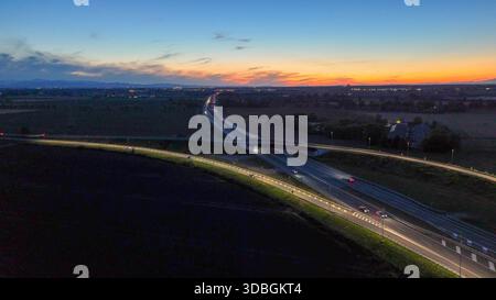 Traffico autostradale percorrendo l'autostrada A21 nei pressi di Piacenza Brescia di notte, veicoli che creano sentieri leggeri sulle infrastrutture e sulla rete stradale durante il sottopassaggio Foto Stock