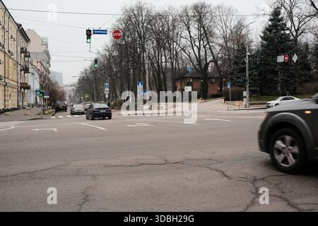 Le auto attraversano un tranquillo angolo urbano circondato da alberi in erba alla luce del mattino. Shevchenko Boulevard. Kiev, Ucraina. 16 dicembre 2025. Foto Stock