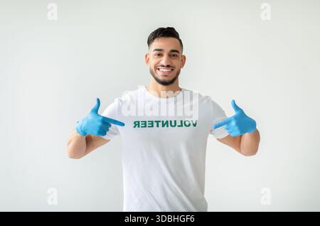 Giovane uomo che indossa con orgoglio una maglietta volontaria al Charity Center, esprimendo felicità Foto Stock