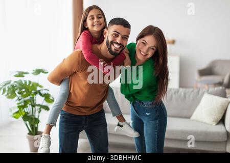 Famiglia araba felice che si diverte a trascorrere momenti ludici insieme nel loro accogliente soggiorno Foto Stock