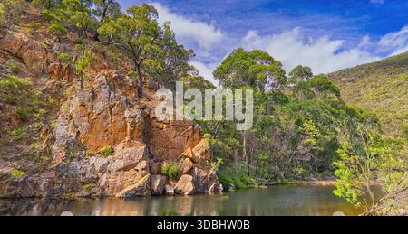 Scogliera di arenaria rocciosa riflessa nella diga di Graham nella gola del fiume Lerderderg in una giornata di sole, nel parco nazionale Wombat-Lerderderg, Victoria, Australia Foto Stock