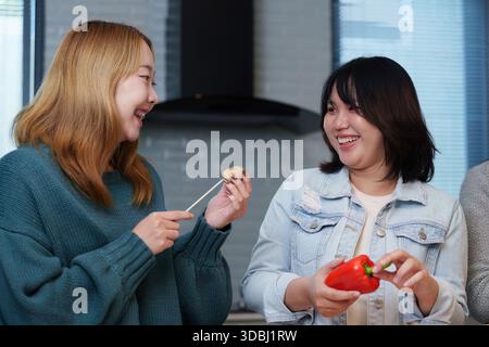 Festa di cucina: Gli amici si divertono con una divertente sessione di cucina con ingredienti freschi Foto Stock