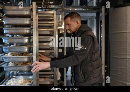 Non esclusivo: Un volontario lavora nella cucina mobile del Food Train, che fornisce pasti caldi alle persone rimaste senza alimentazione e riscaldamento a causa di un russo Foto Stock