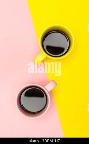Lay piatto vista dall'alto di due tazze da caffè con rosa e giallo. Foto Stock