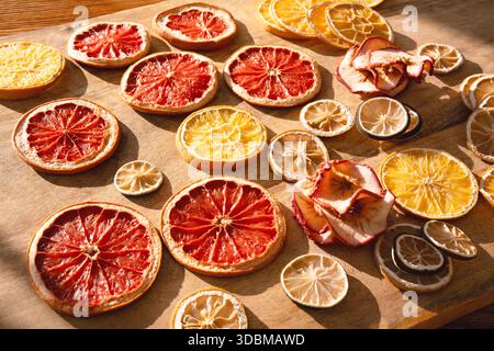 Vari agrumi secchi per l'inverno e il periodo natalizio. Affettare frutta secca con anelli di mele su legno. Preparativi per le celebrazioni di natale. Foto Stock
