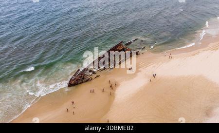 Vista aerea dello scheletro arrugginente del relitto della SS Maheno arenato sulla spiaggia sabbiosa con le onde dell'oceano che si infrangono, Fraser Island, Queensland, Au Foto Stock