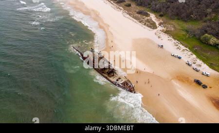 Vista aerea del relitto arrugginito della SS Maheno in contrasto con le sabbie dorate e le onde turchesi, Fraser Island, Queensland, Australia. Foto Stock