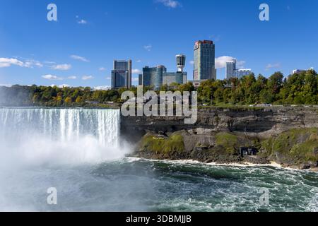 Veduta aerea della potente cascata delle Cascate del Niagara che si schianta nel fiume sottostante, incorniciata dallo skyline, Niagara Falls, Ontario, Canada. Foto Stock