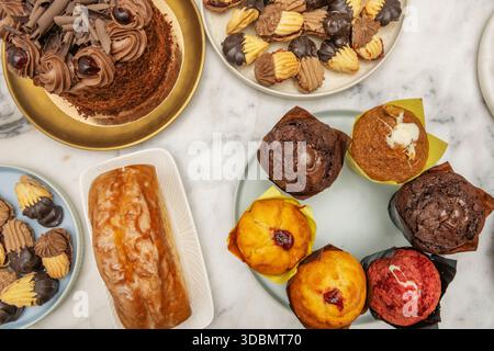 Doppio muffin al cioccolato con gocce di cioccolato bianco e fondente nell'impasto, ricoperto di crema ganache e una fragola fresca Foto Stock